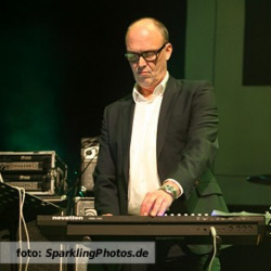 Etalageblokje voor De platenkast van Wim Dekker, interview over en met muziek. Het beeld is Wim Dekker die op het podium staat met zijn synthesizers en laptop. Foto geschoten door een fotograaf van www.SparklingPhotos.de